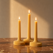 Three lit candles on a marble surface with a neutral background