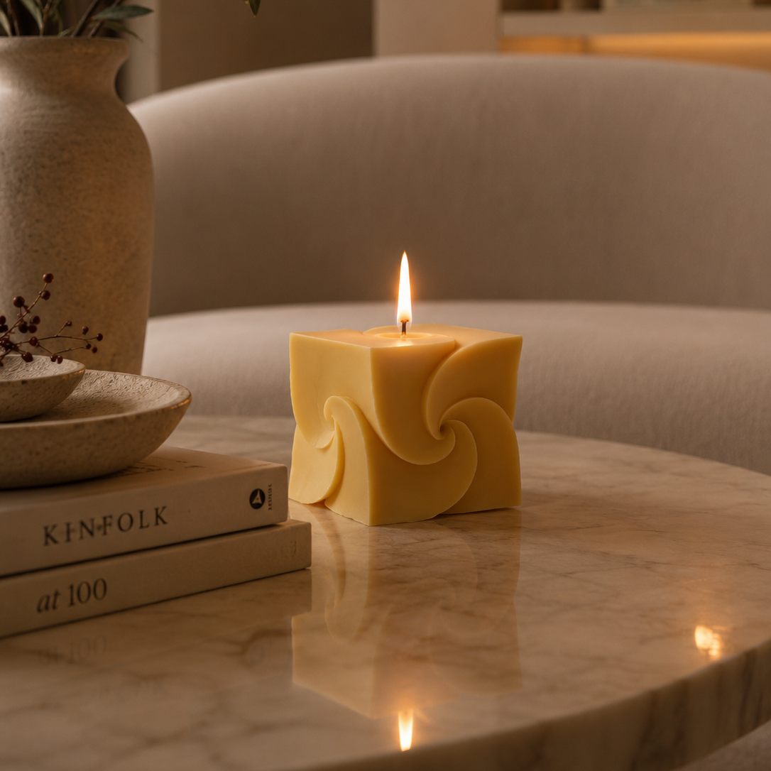 Decorative candle on a marble surface with books and a vase in the background