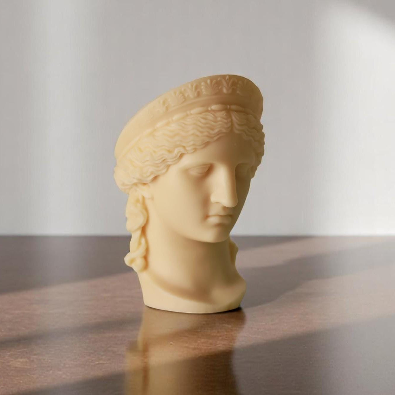 Statue head on a wooden surface with a neutral background